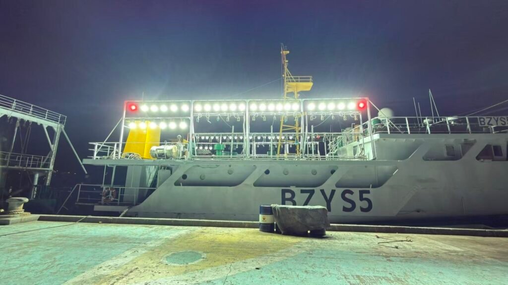 Commercial fishing vessel illuminated by deck and attracting lights at night