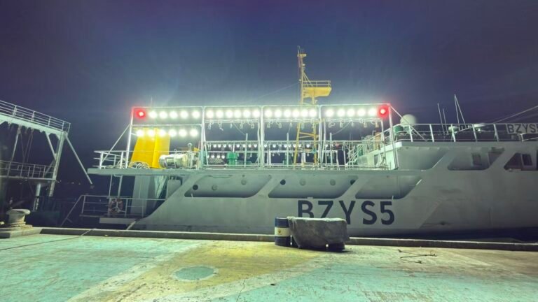 Commercial fishing vessel illuminated by deck and attracting lights at night